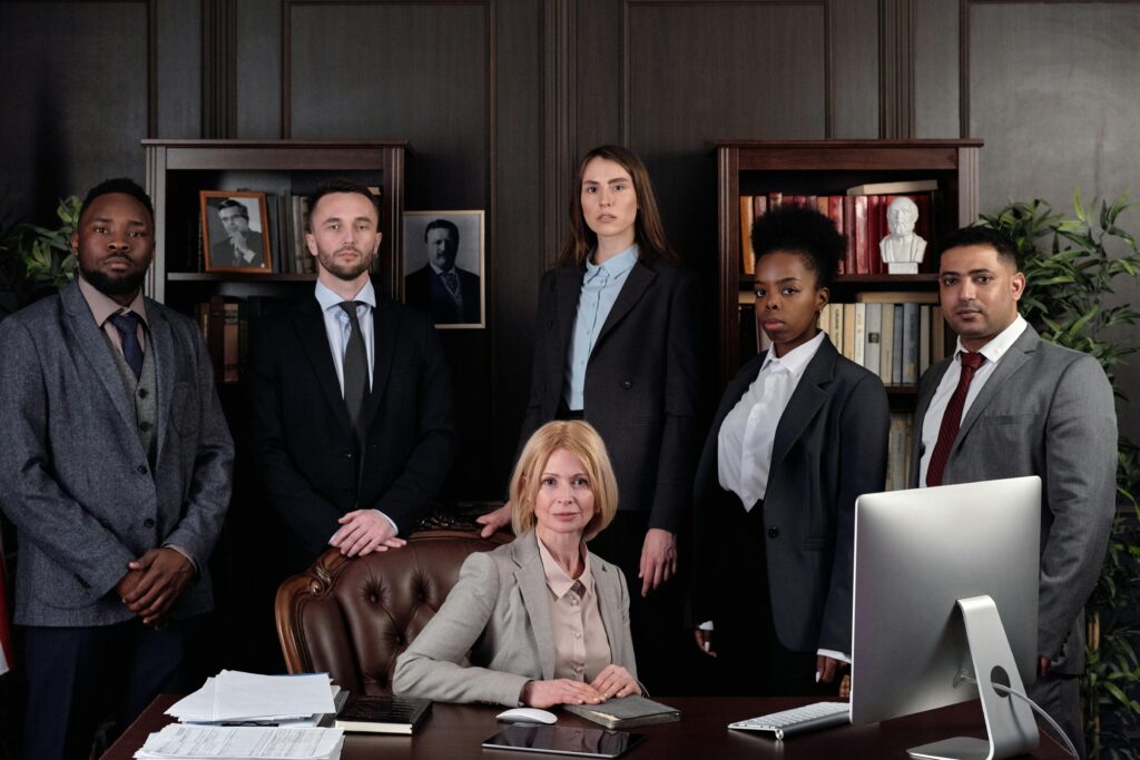 Six business professionals in formal attire posing in an office.